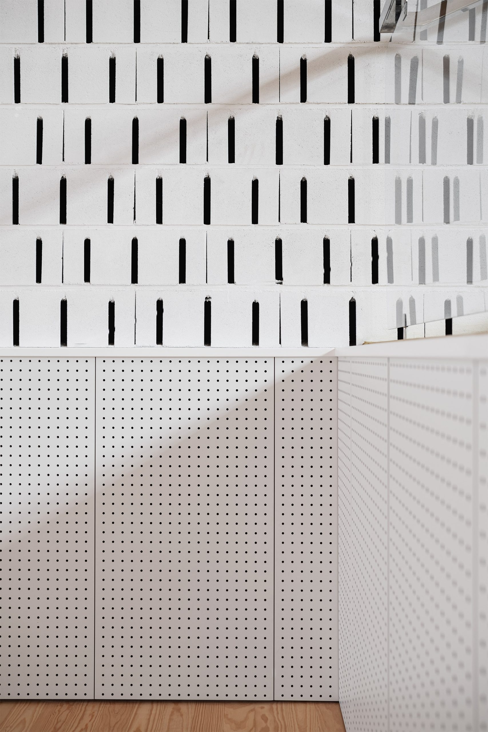 Bancadas amarelas com cadeiras verdes e parede ventilada em bloco branco