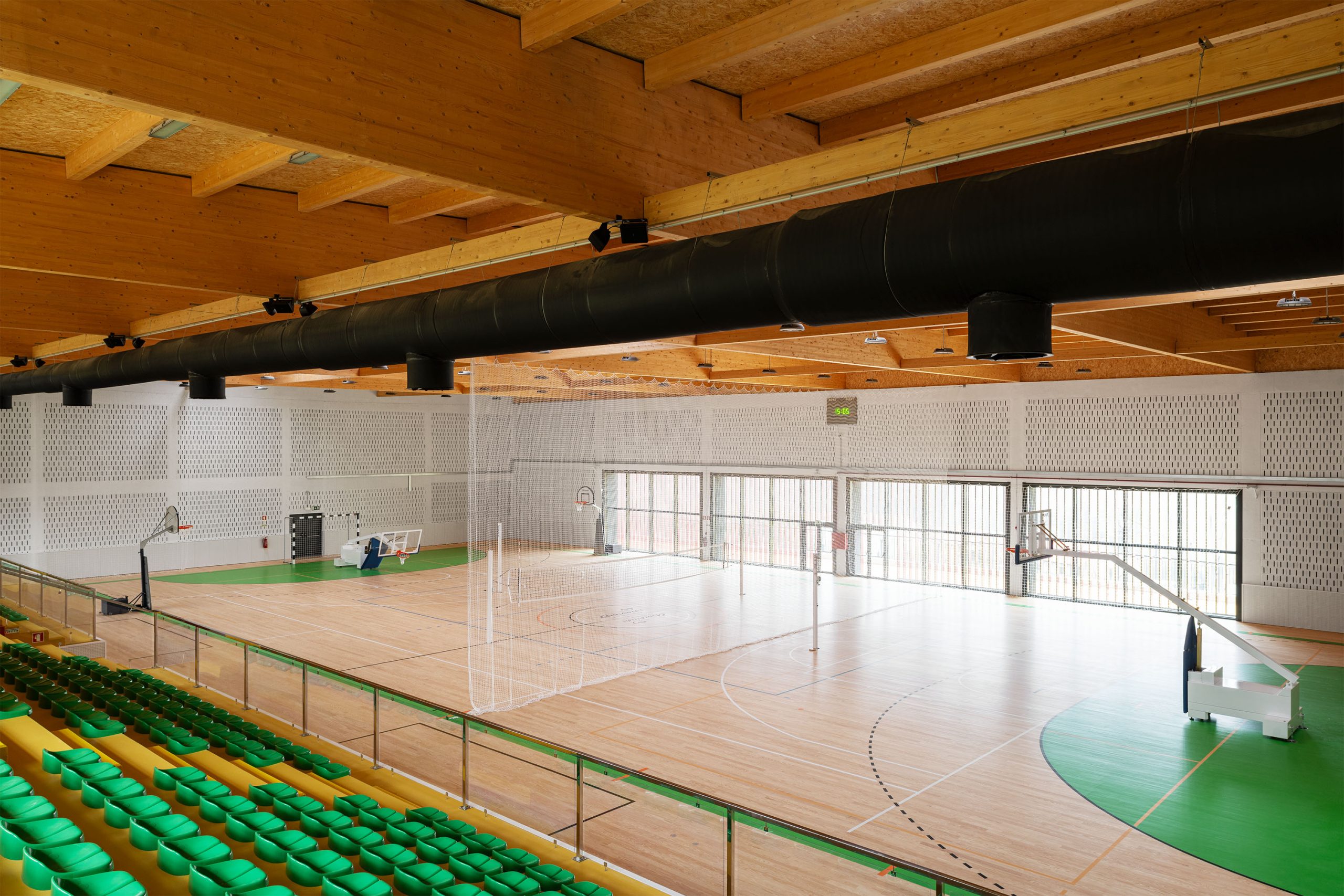 Corredor com piso amarelo e sinalética de acessibilidade junto a guardas envidraçadas