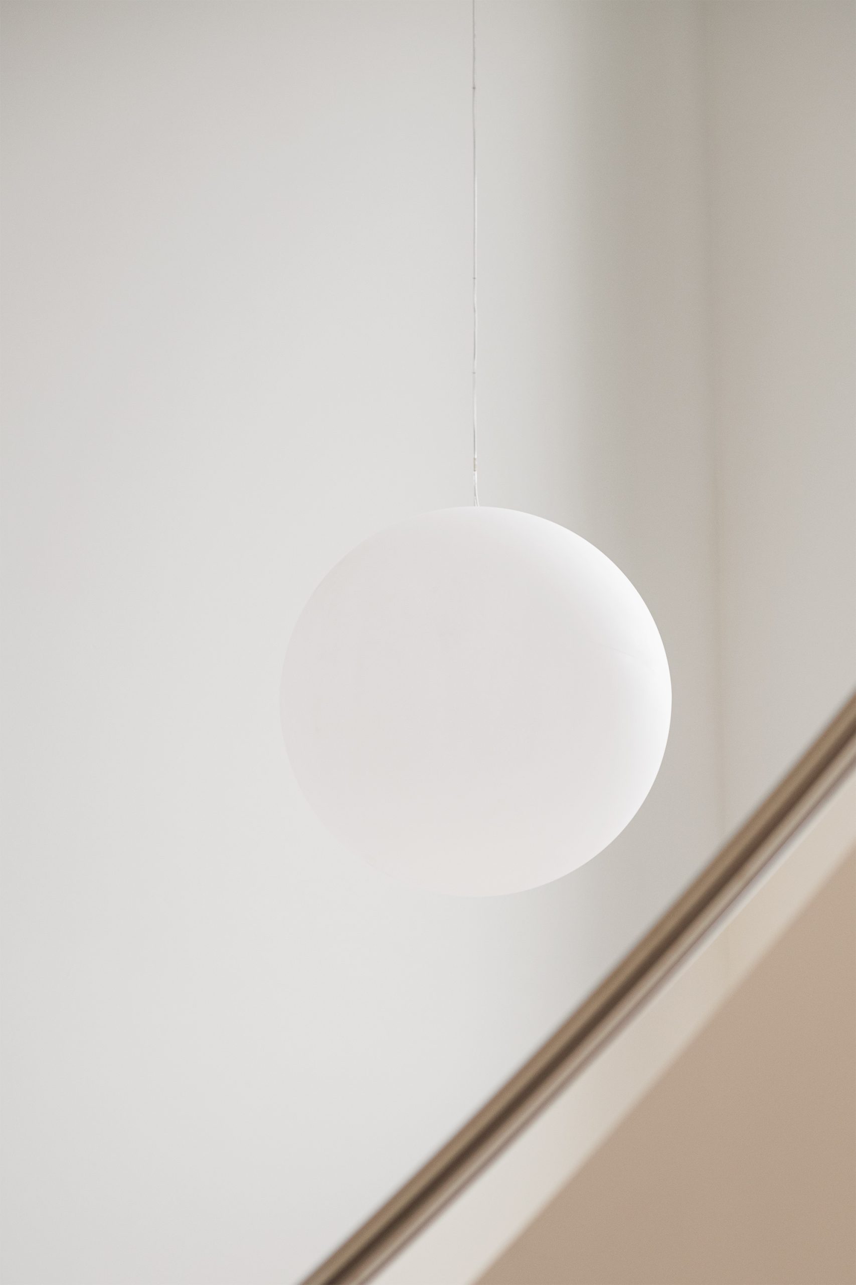 Luminárias esféricas suspensas em espaço branco com geometria angular