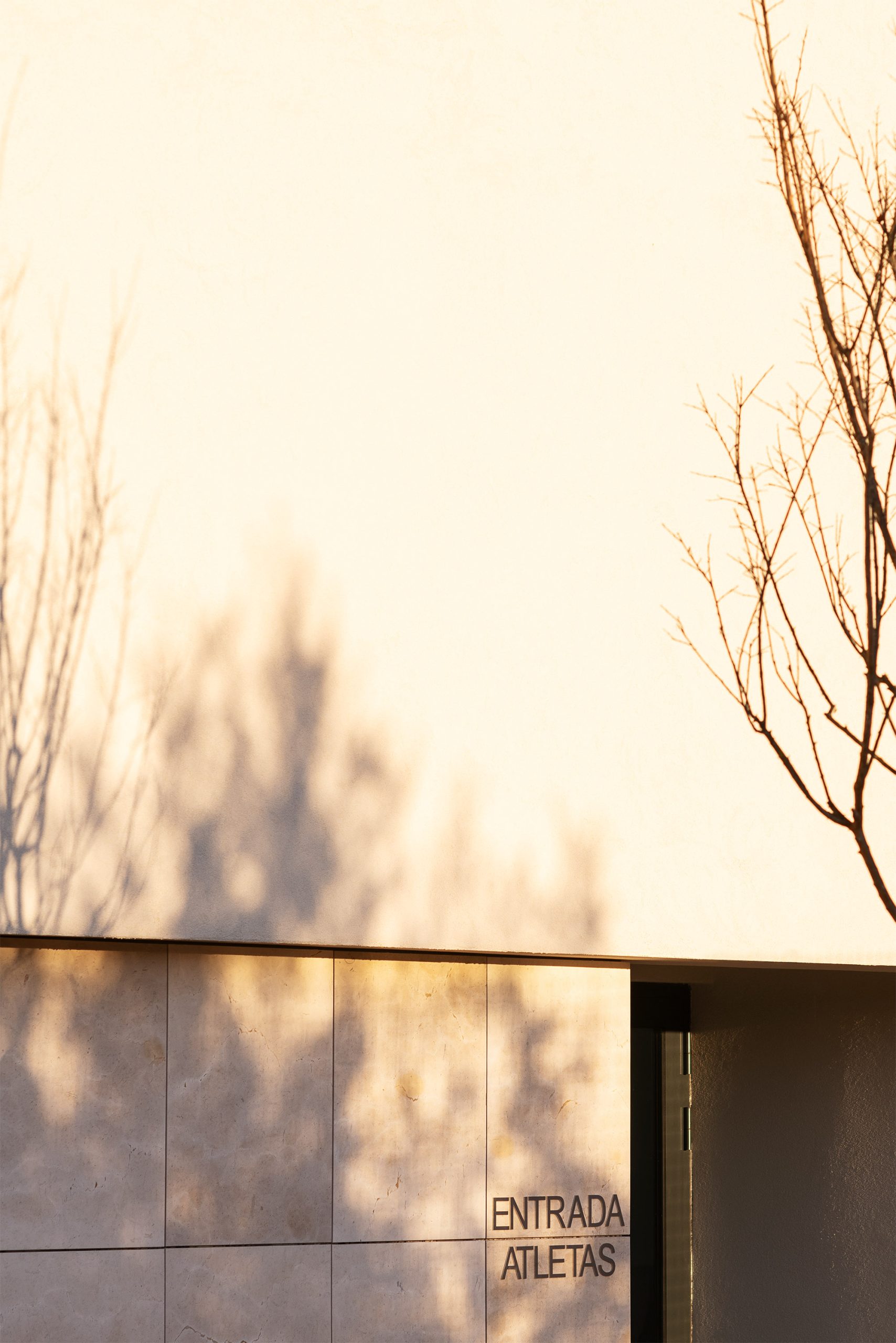 Fachada dourada metálica ao pôr do sol com escadaria frontal em betão