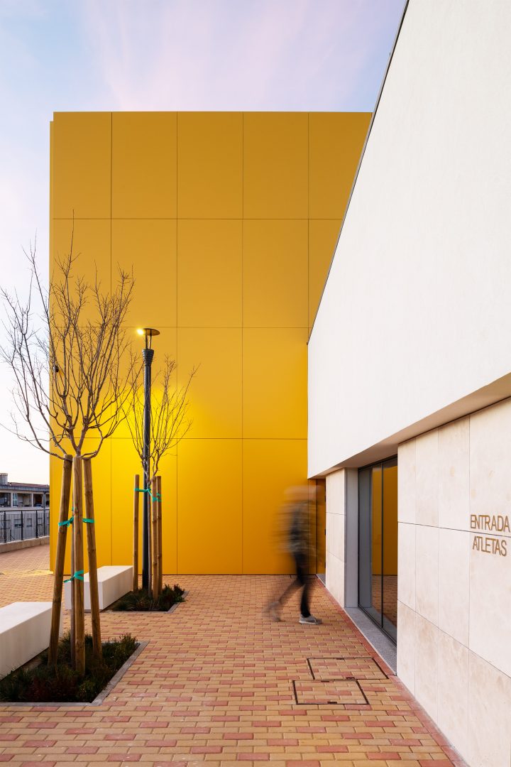 Fachada dourada metálica ao pôr do sol com escadaria frontal em betão