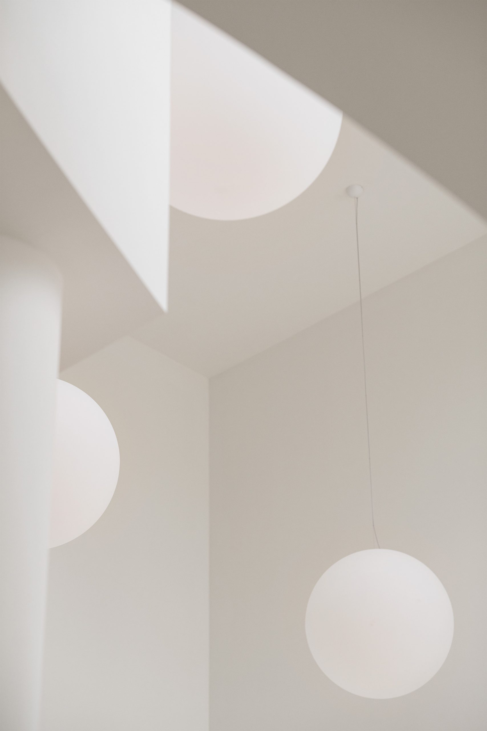 Luminárias esféricas suspensas em espaço branco com geometria angular