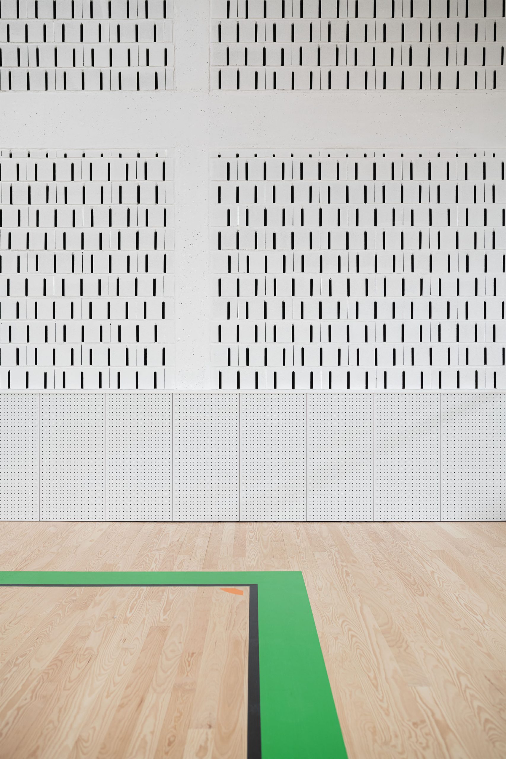 Bancadas amarelas com cadeiras verdes e parede ventilada em bloco branco