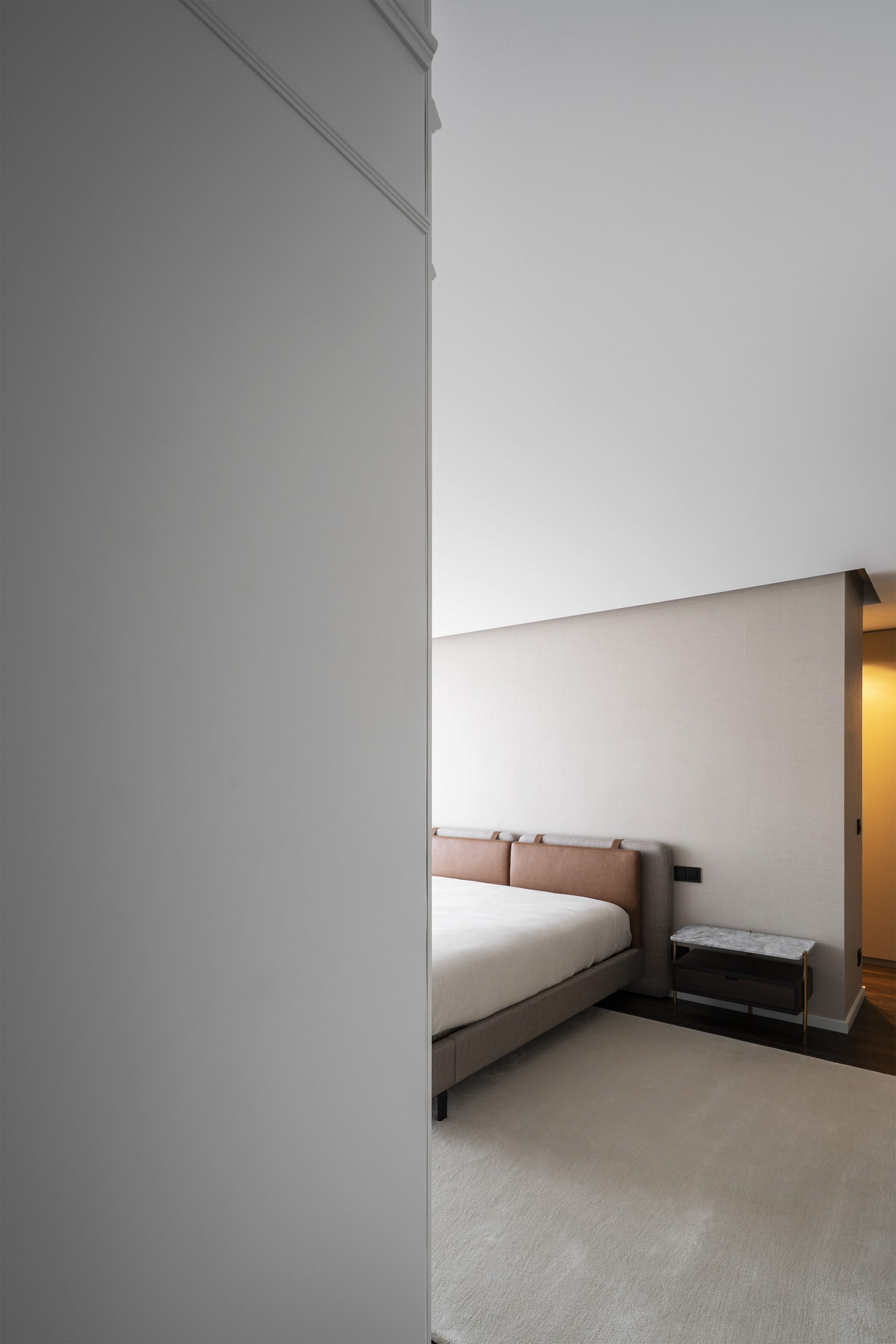 Quarto com cabeceira em pele e pendente minimalista junto a cortina translúcida