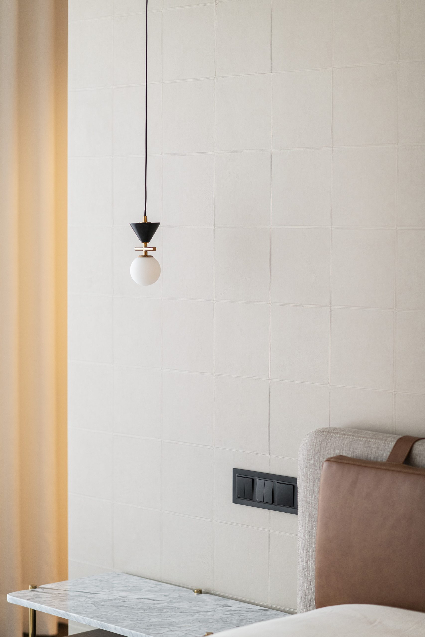 Quarto com cabeceira em pele e pendente minimalista junto a cortina translúcida