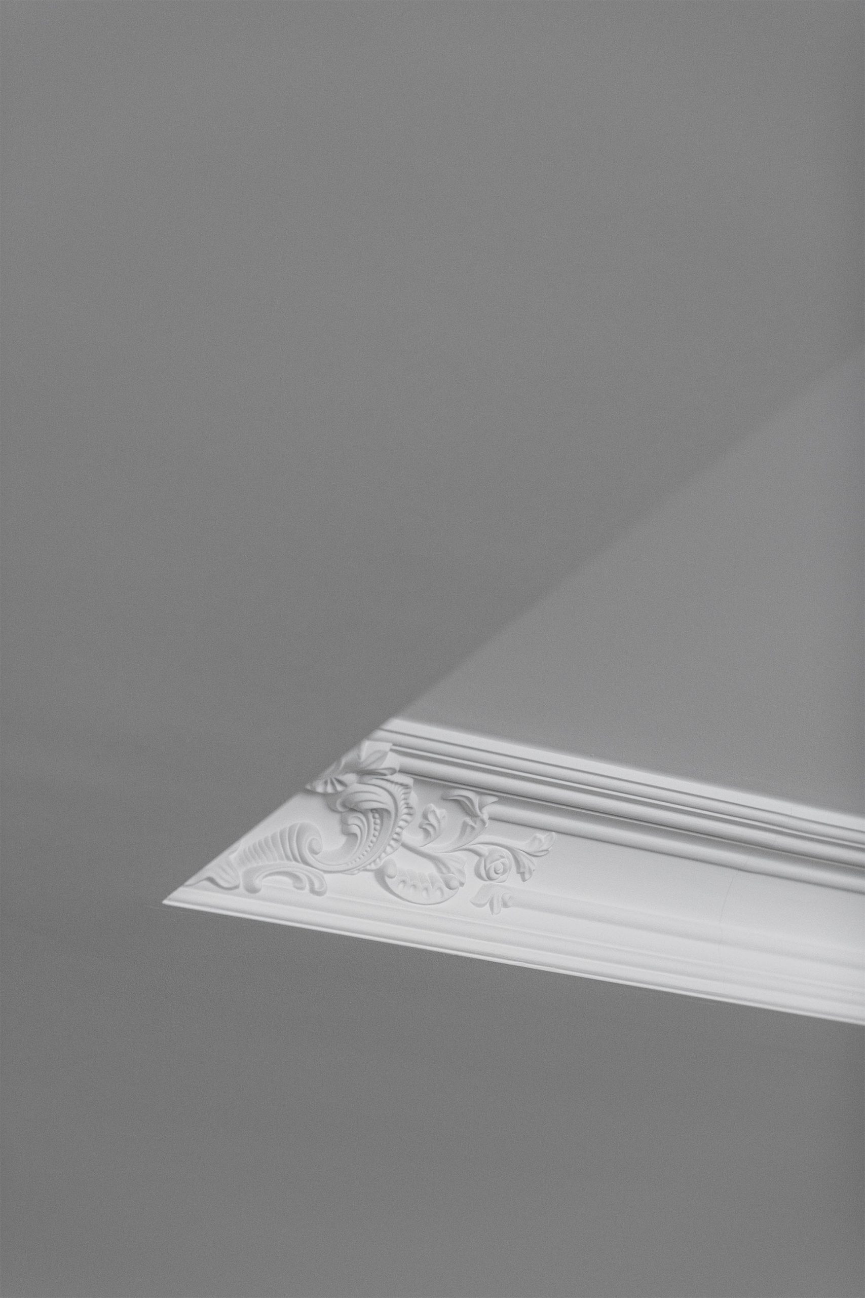 Luminária circular suspensa sobre mesa escura com armário iluminado ao fundo