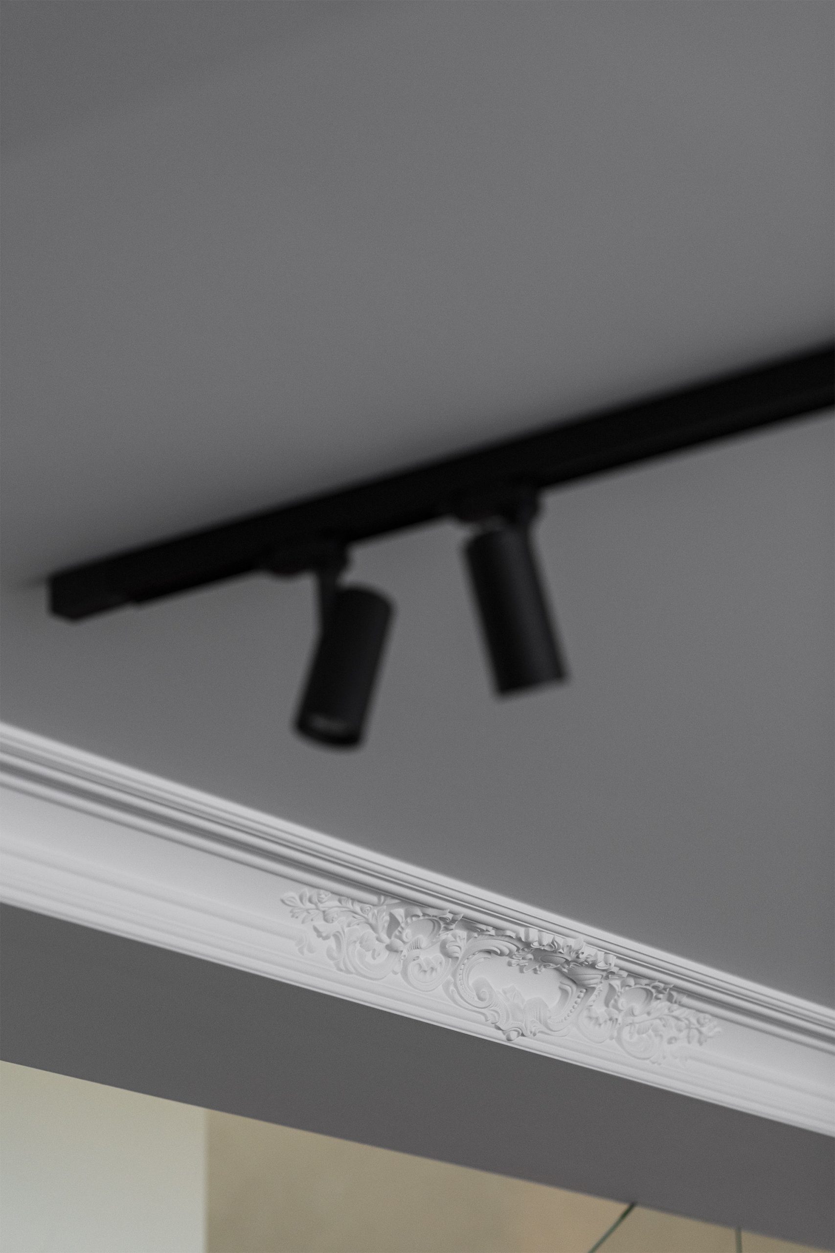 Luminária circular suspensa sobre mesa escura com armário iluminado ao fundo