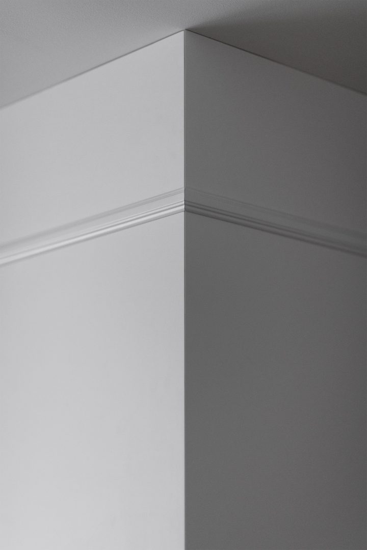 Luminária circular suspensa sobre mesa escura com armário iluminado ao fundo