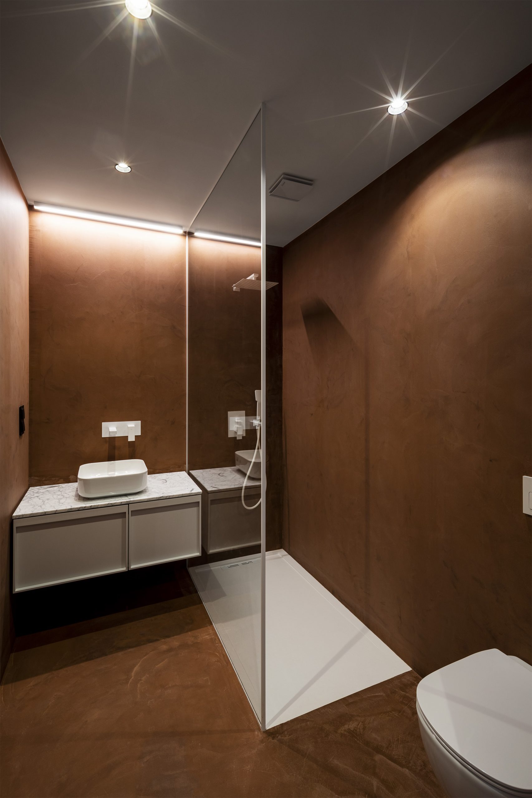 WC contemporâneo com revestimento argiloso e duche com torneiras brancas