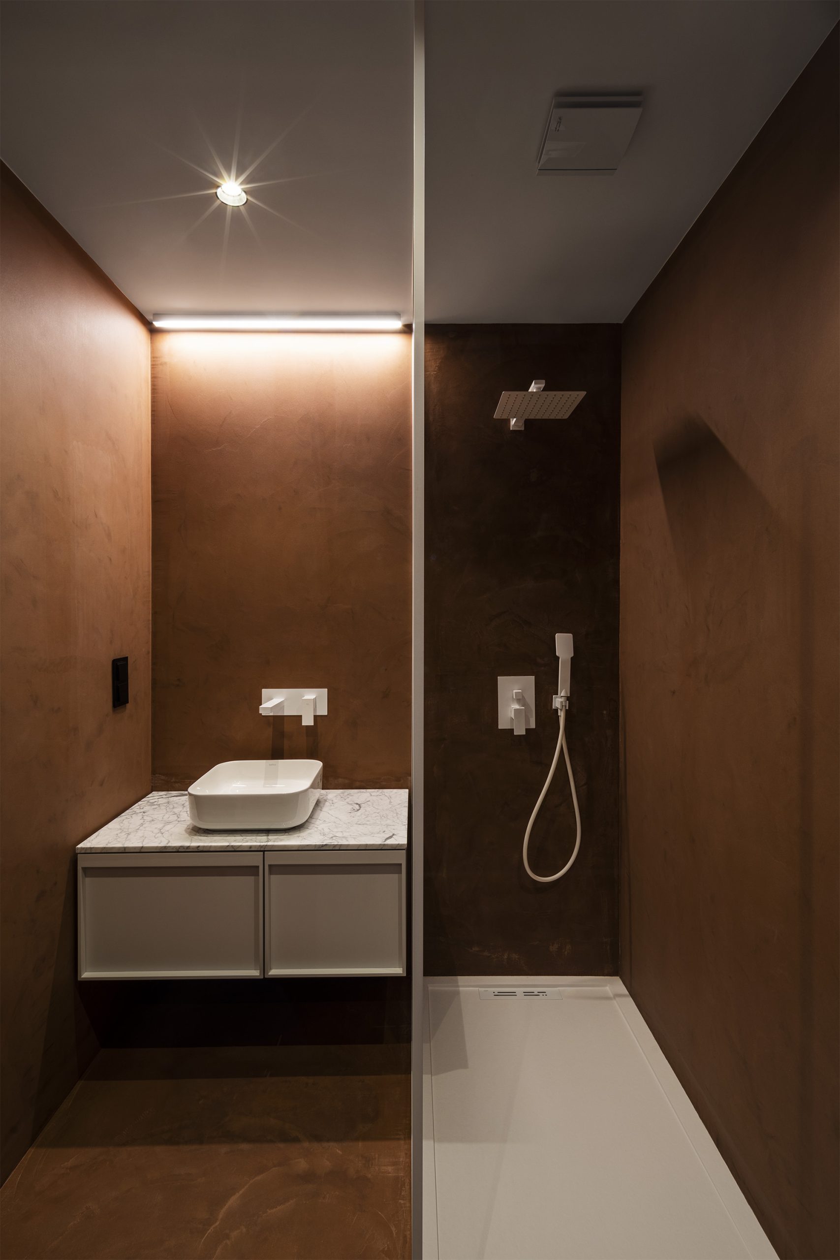 WC contemporâneo com revestimento argiloso e duche com torneiras brancas