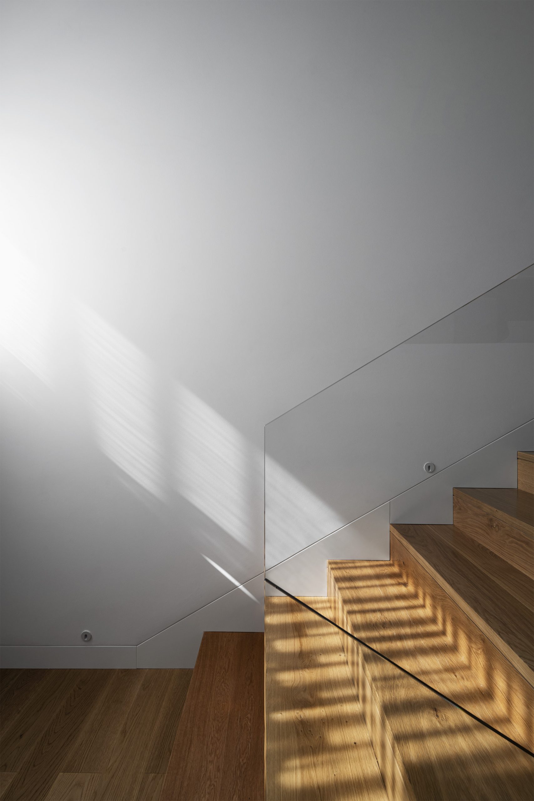 Detalhe de escada em madeira com sombra projetada no plano branco