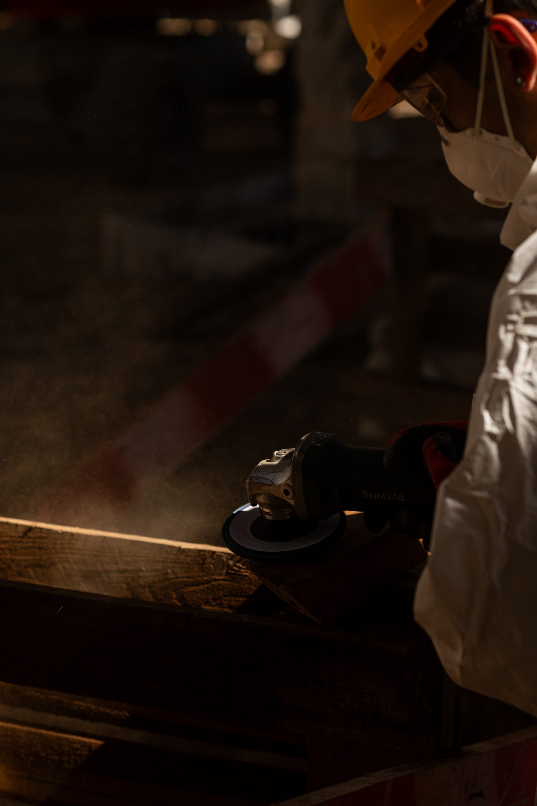 Operário com equipamento de proteção individual a trabalhar com luz dramática