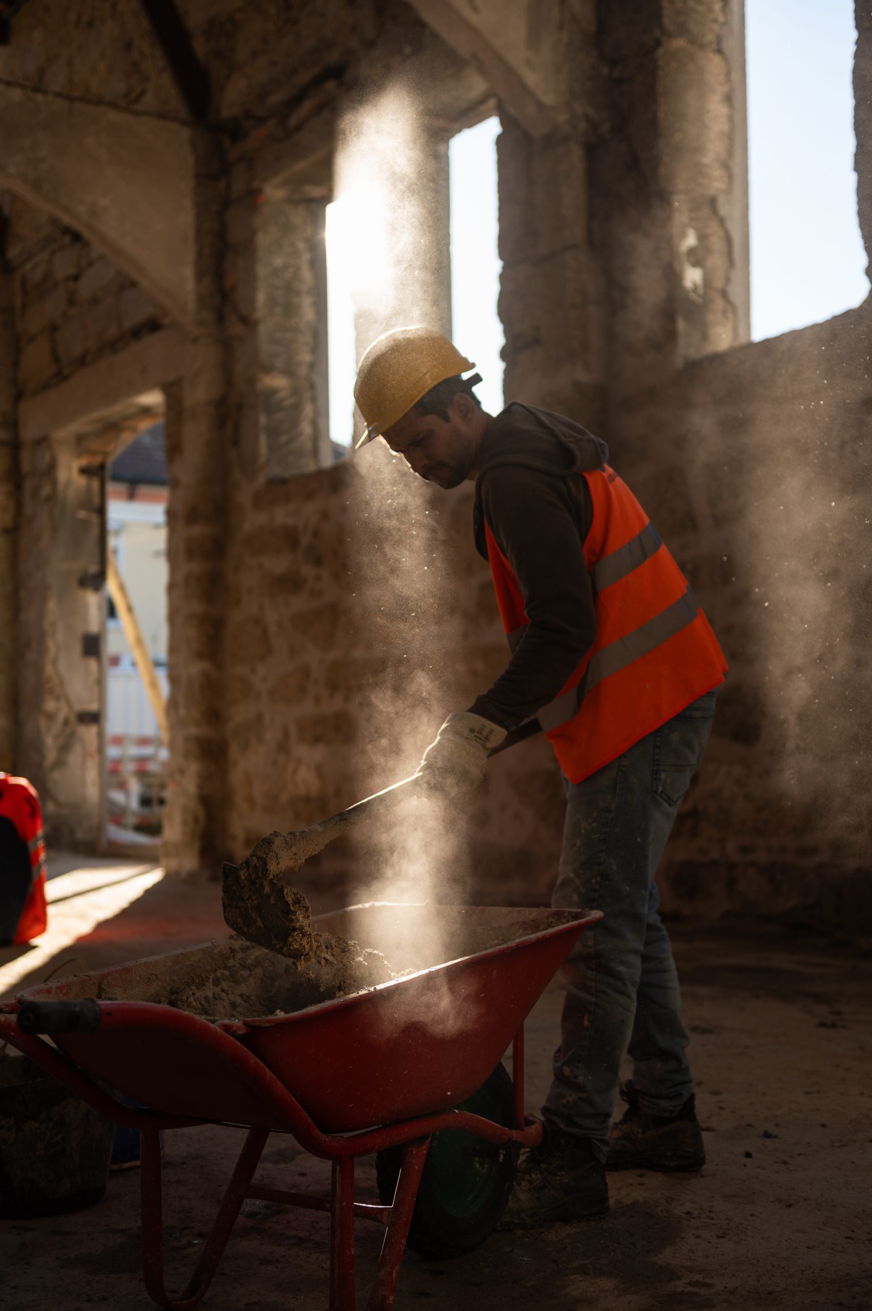 Trabalhador a misturar cimento sob luz intensa no estaleiro do Matadouro do Porto
