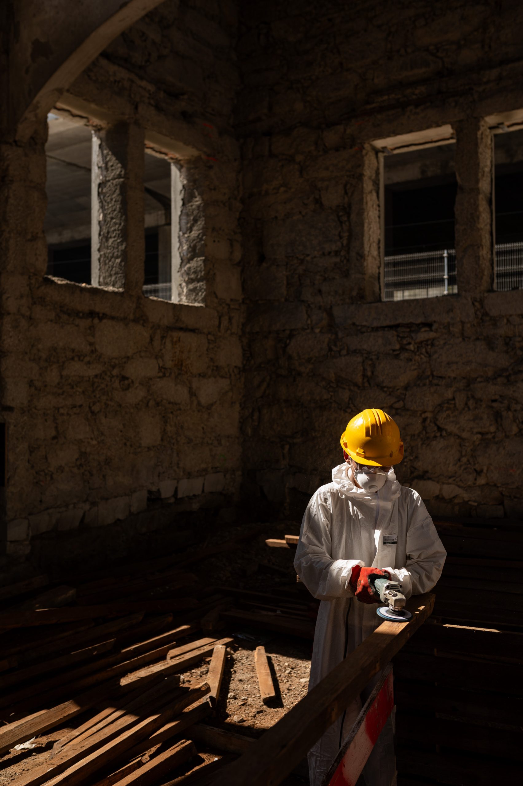Operário a lixar madeira com rebarbadora durante a obra de reabilitação