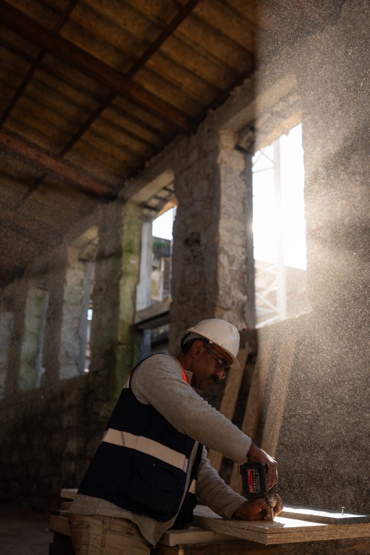 Operário a lixar madeira com rebarbadora durante a obra de reabilitação