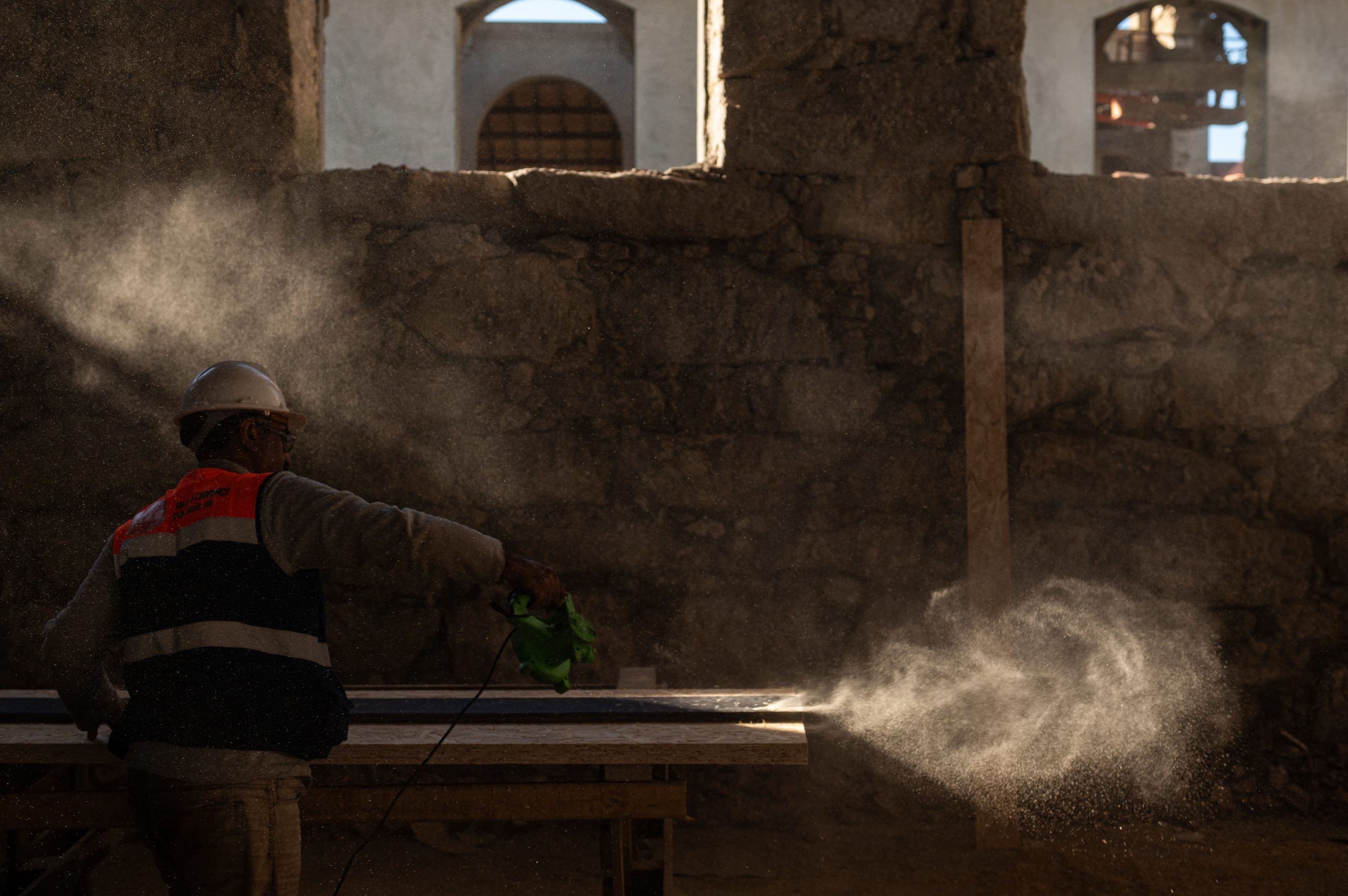 Operário a lixar madeira com rebarbadora durante a obra de reabilitação