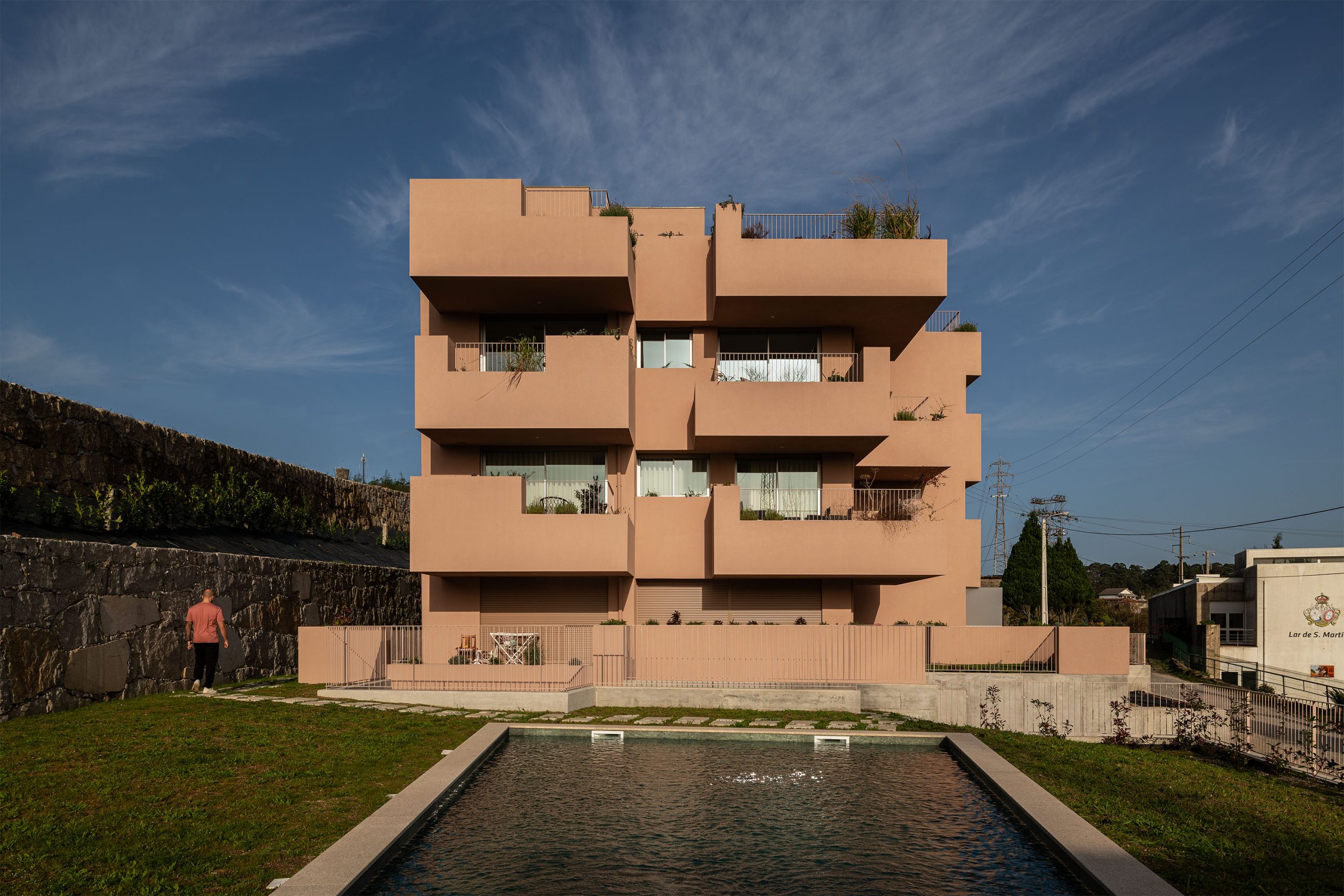 Fachada principal da habitação multifamiliar CFDS Architecture em Penafiel com planos alternados e cor laranja.