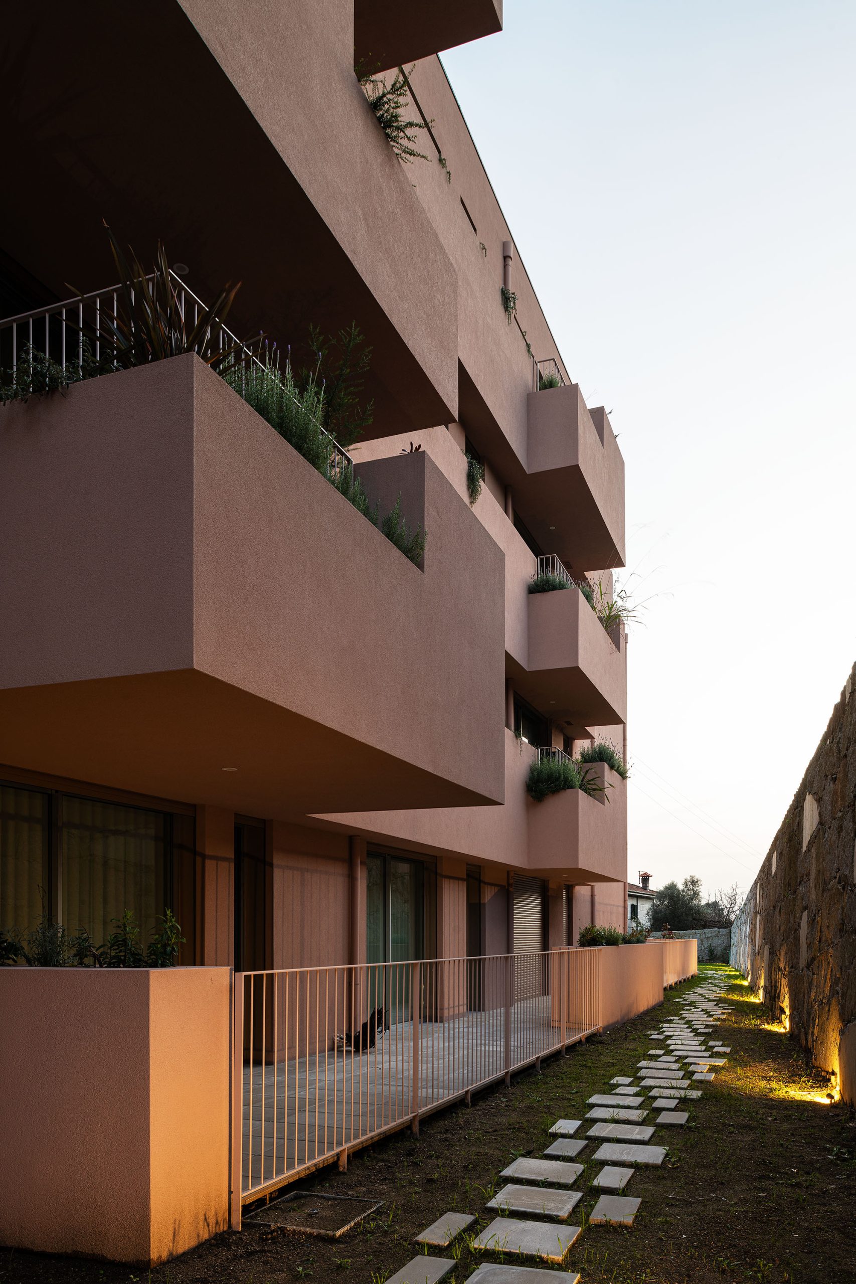 Fachada principal da habitação multifamiliar CFDS Architecture em Penafiel com planos alternados e cor laranja.