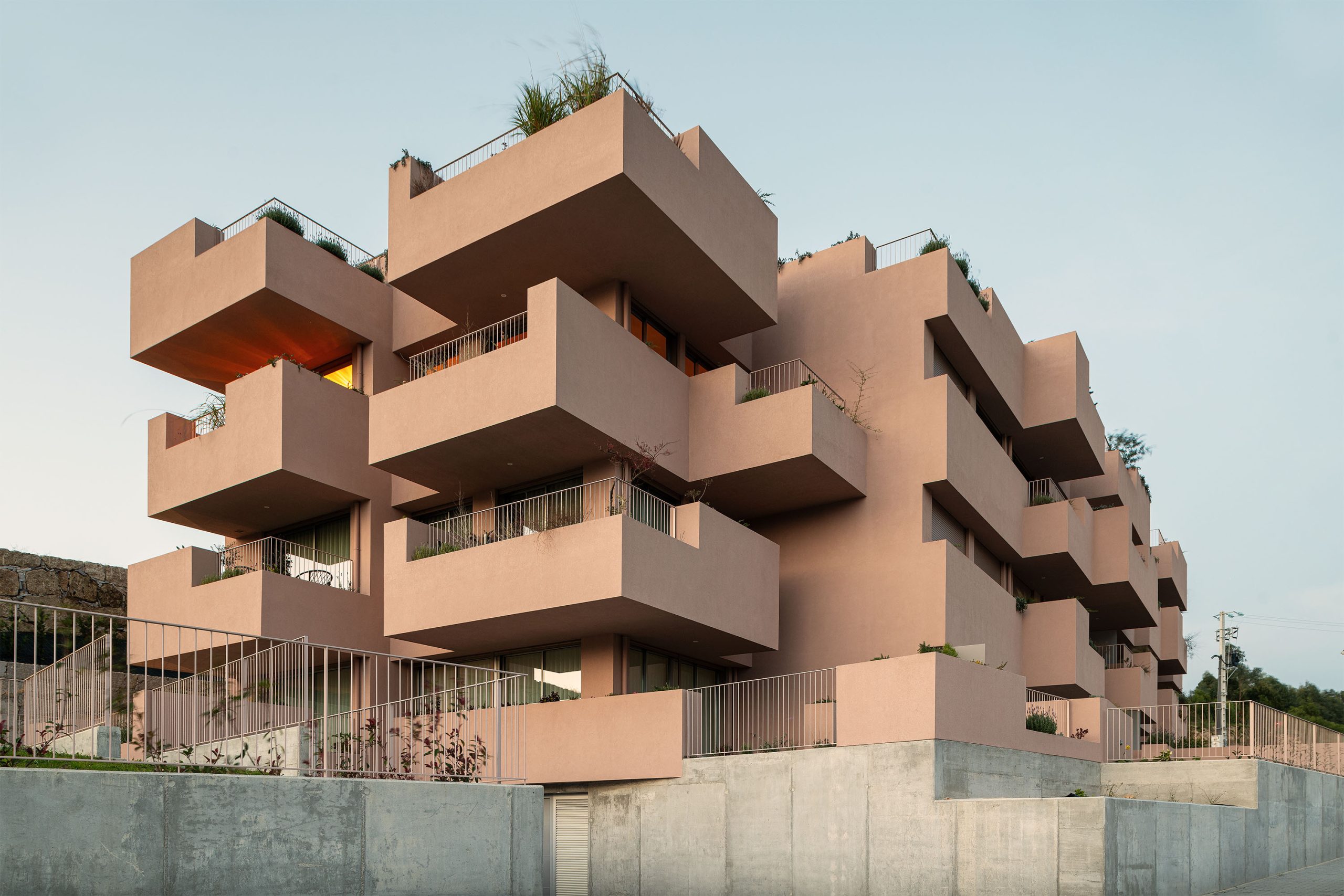 Fachada principal da habitação multifamiliar CFDS Architecture em Penafiel com planos alternados e cor laranja.